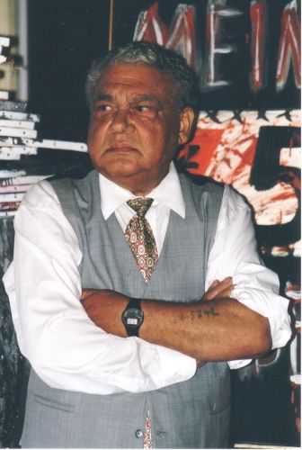 Porträtfoto eines stehenden Mannes mit verschränkten Armen